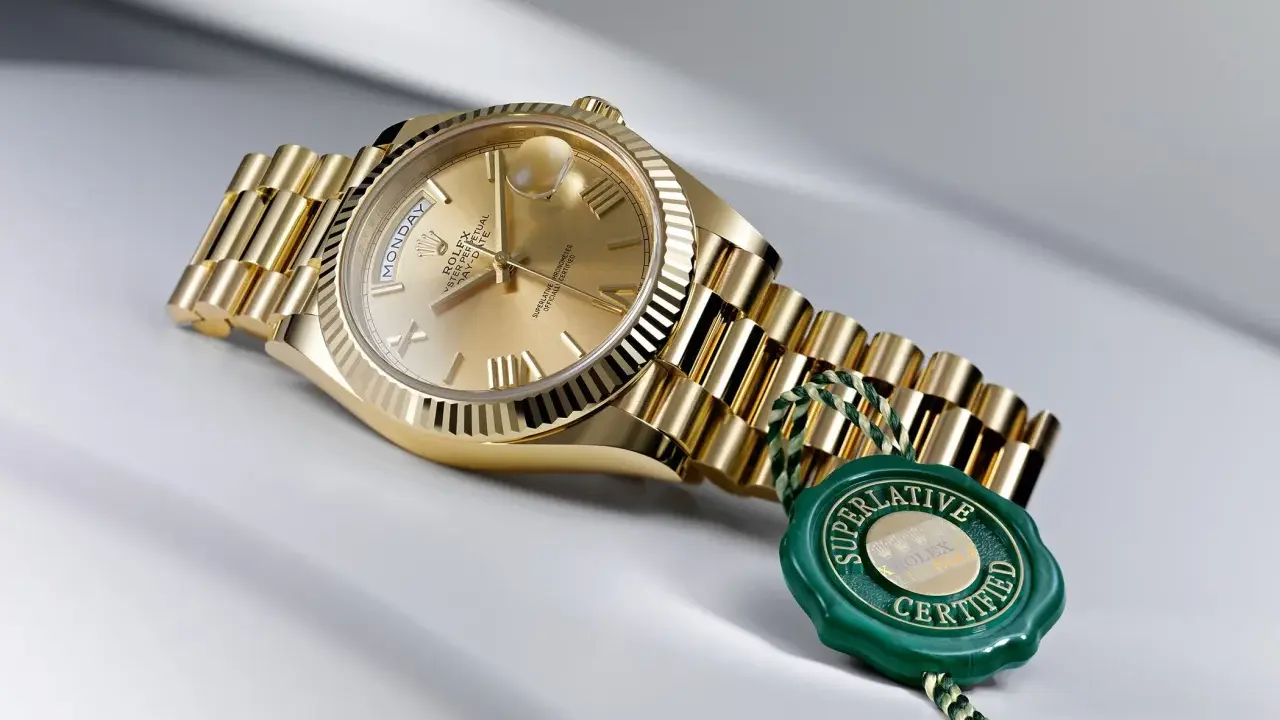 Złoty zegarek Rolex, jak brat szpaka, lśni na jasnym tle. Zielona pieczęć "Superlative Certified" podkreśla jego prestiż.