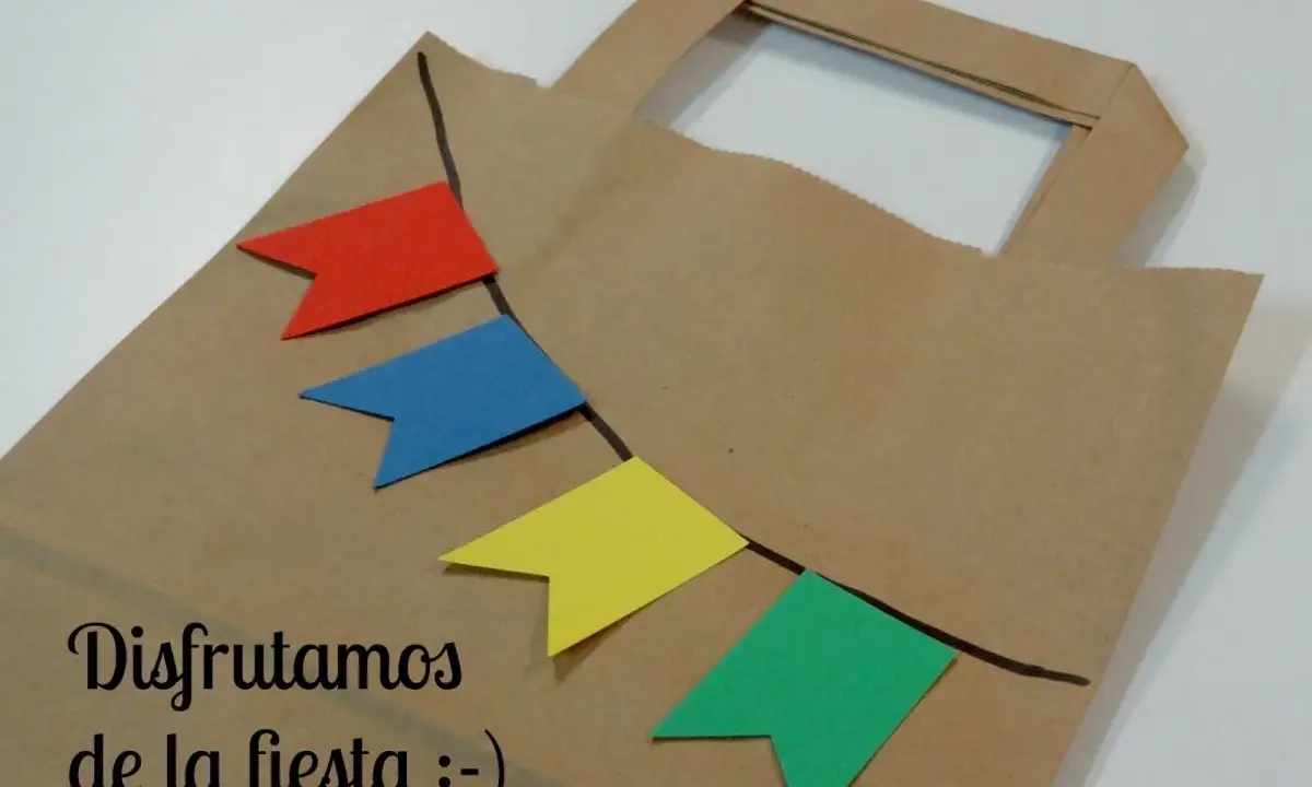 Bolsa de papel decorada con banderines de colores, ideal para hacer bolsas de chuches caseras y disfrutar de la fiesta.