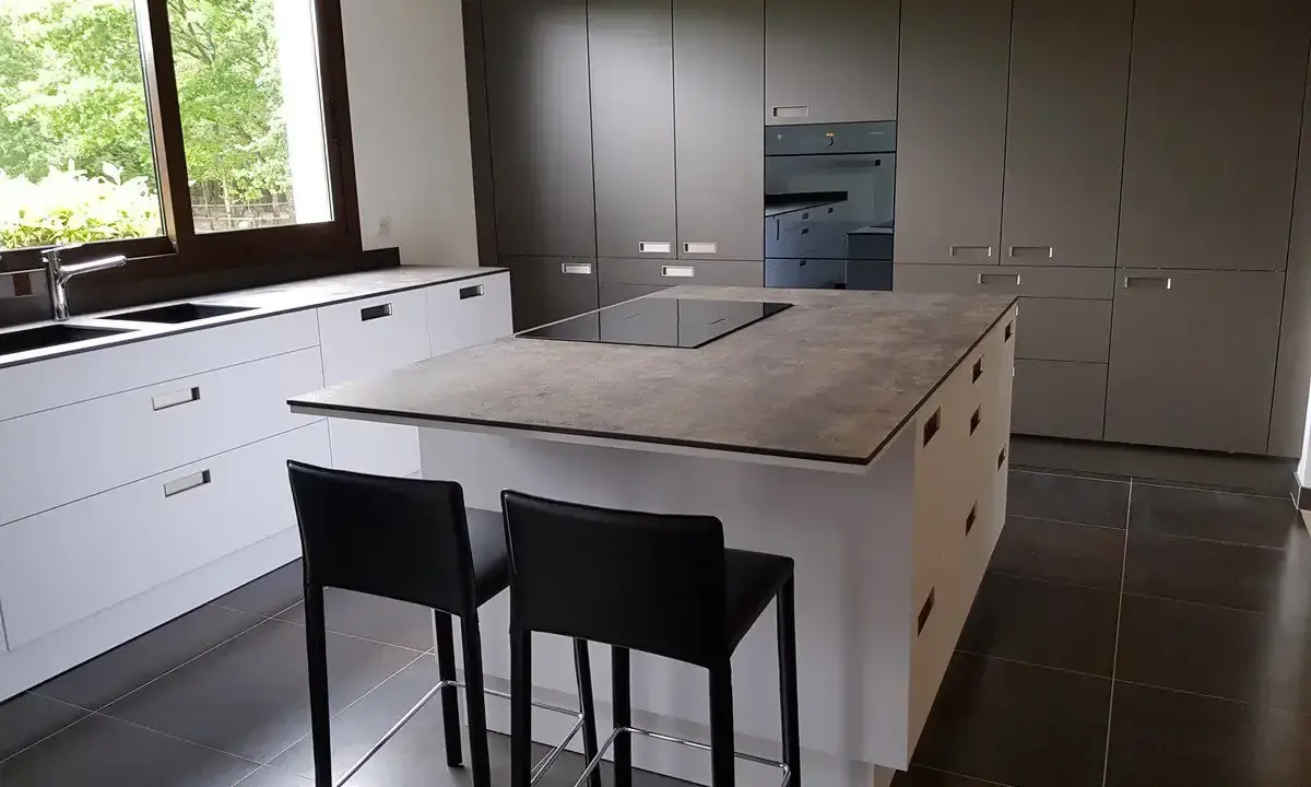 Cuisine moderne avec îlot central. On peut facilement faire le tour de cet îlot central pour accéder aux plans de travail et aux tabourets.