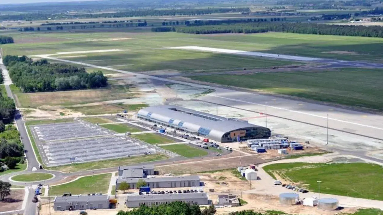Lotnisko Warszawa Modlin z lotu ptaka: nowoczesny terminal, pas startowy i rozległe tereny zielone.