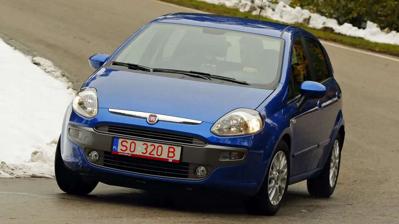 Niebieski Fiat z polskimi tymczasowymi tablicami rejestracyjnymi SO 320 B jedzie po krętej drodze, po bokach śnieg.