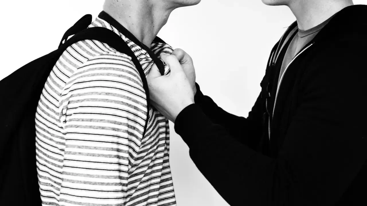 Due persone, una con una felpa nera, afferra l'altra per il colletto. Un'immagine che evoca la psicologia delle persone aggressive.
