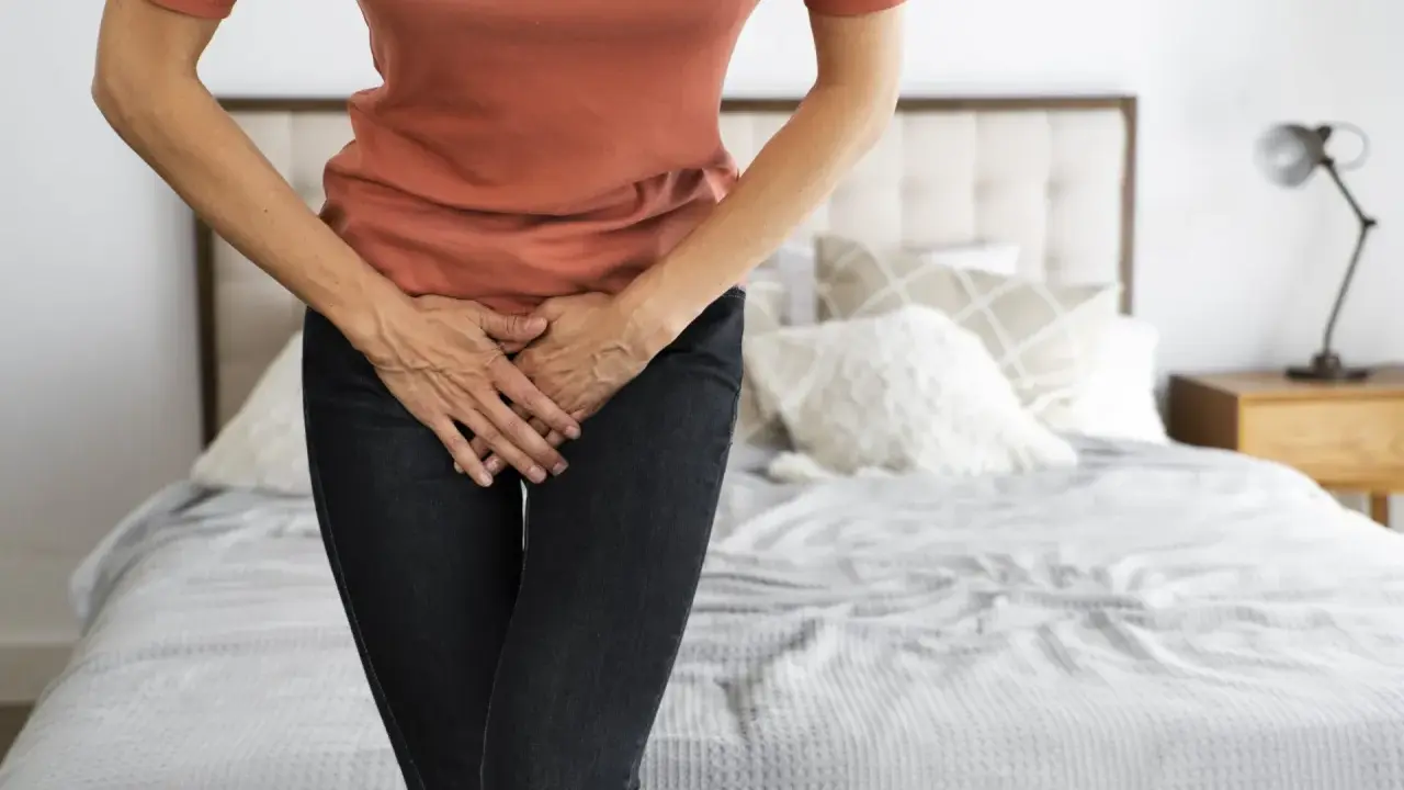 Mujer con las manos en el abdomen, sintiendo dolor de ovarios y gases.