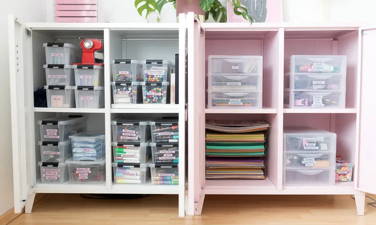 Ein aufgeräumter Bastelschrank mit vielen beschrifteten Boxen, die FIMO, Marker und Bastelmaterialien enthalten. Alles ist perfekt organisiert.