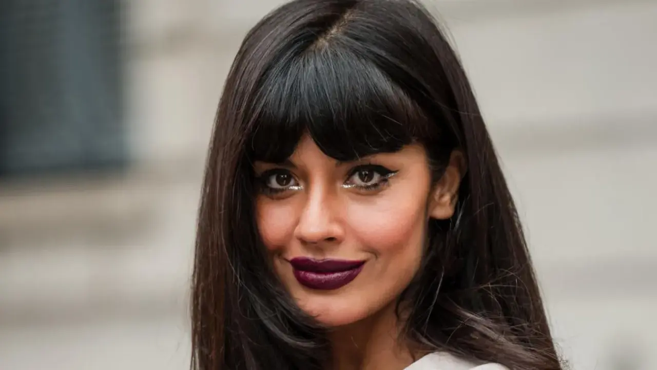 Frau mit leichter Pony und langen, dunklen Haaren, auffälligem Make-up und dunklem Lippenstift.