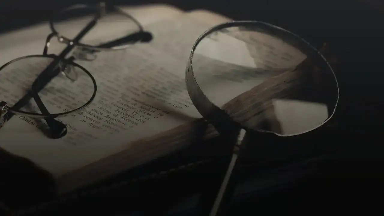 Brille und Lupe über einem alten Buch, bereit für eine tiefgehende Gedichtanalyse.