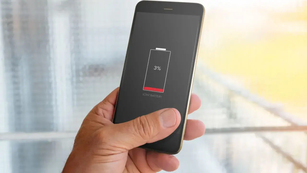 En hand håller en mobil med lågt batteri, 3%. Dags att kolla vilka appar som drar mest batteri.