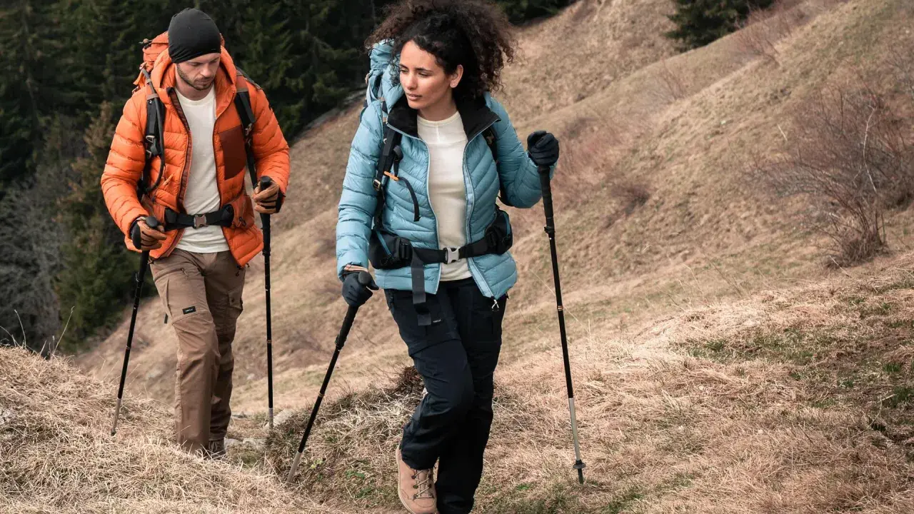 Para dobrać kije trekkingowe do wzrostu, zwróć uwagę na kąt 90 stopni w łokciu podczas marszu. Para turystów z kijkami na górskim szlaku.