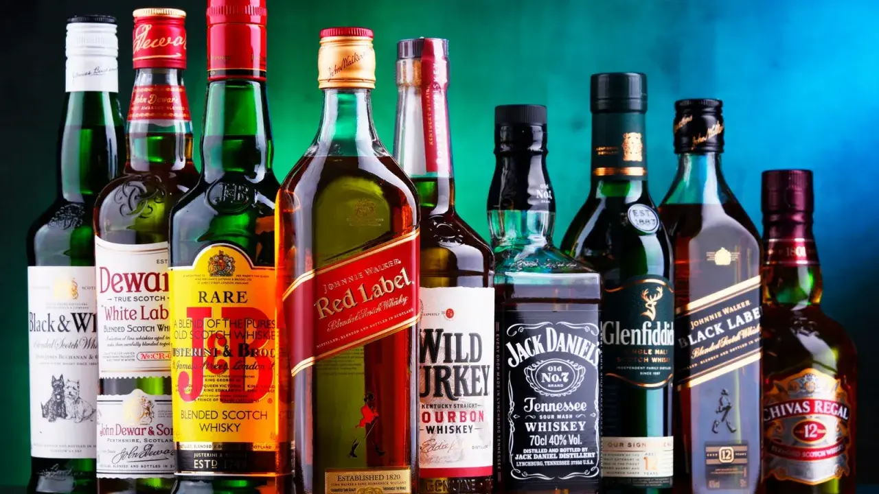 Eine Reihe von Whiskyflaschen, darunter Johnnie Walker Red Label, Jack Daniel's und Chivas Regal. Die Frage "wie viel prozent hat whisky" wird durch die 40% Vol. auf der Jack Daniel's Flasche beantwortet.