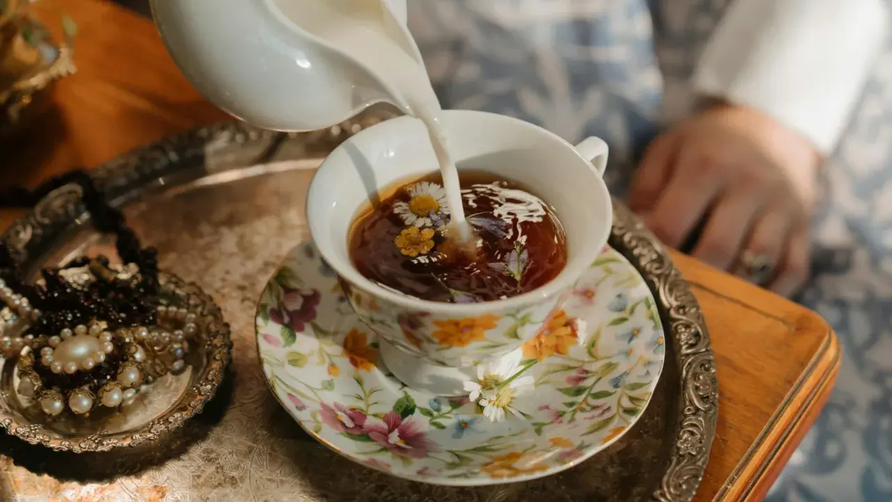 Té floral servido en una taza decorada, perfecto para celebrar los 20 años de casados. Un detalle de joyas antiguas añade elegancia.
