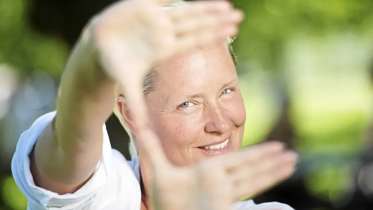 Regina Lund ler inramad av sina händer, som om hon skapar en scen för en film.