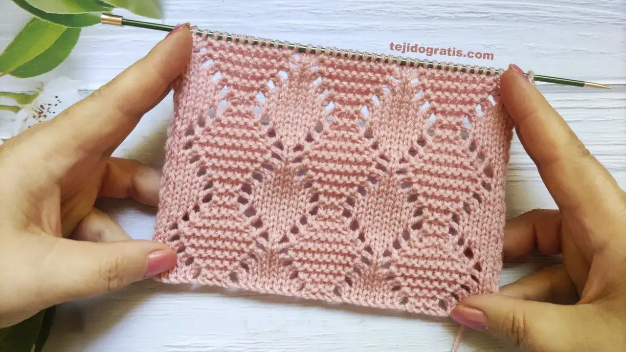 Muestra de tejido rosa con rombos a dos agujas patrones calados, ideal para prendas delicadas.