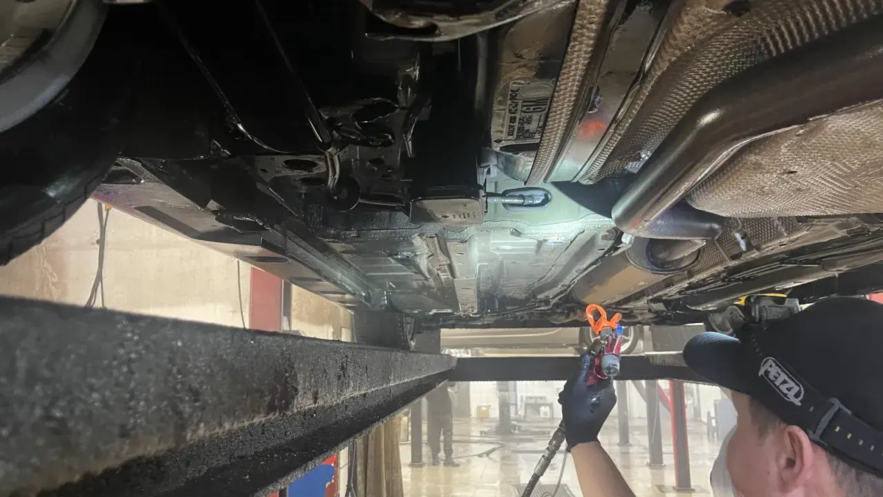 Profesjonalne zabezpieczenie antykorozyjne podwozia samochodu. Mechanik aplikuje preparat ochronny.