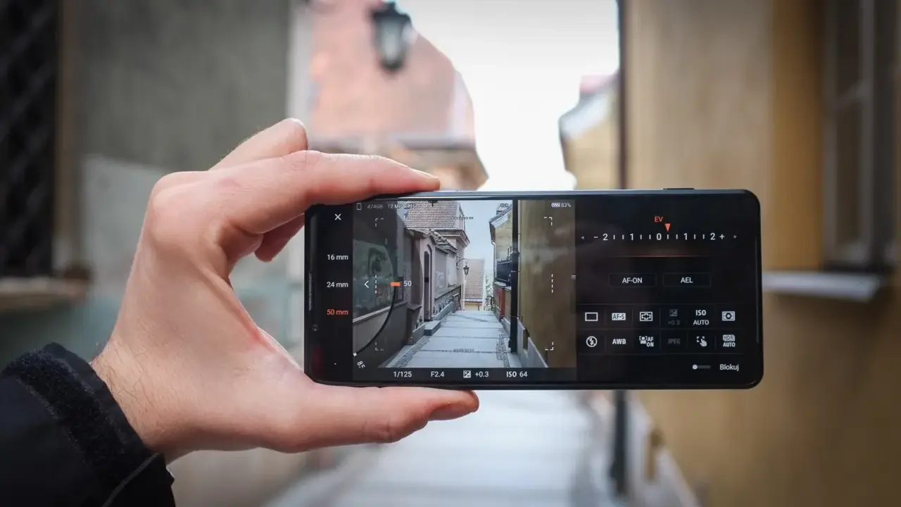 Dłoń trzyma smartfon Sony Xperia Pro i, kadrując wąską uliczkę. Widoczne ustawienia aparatu.