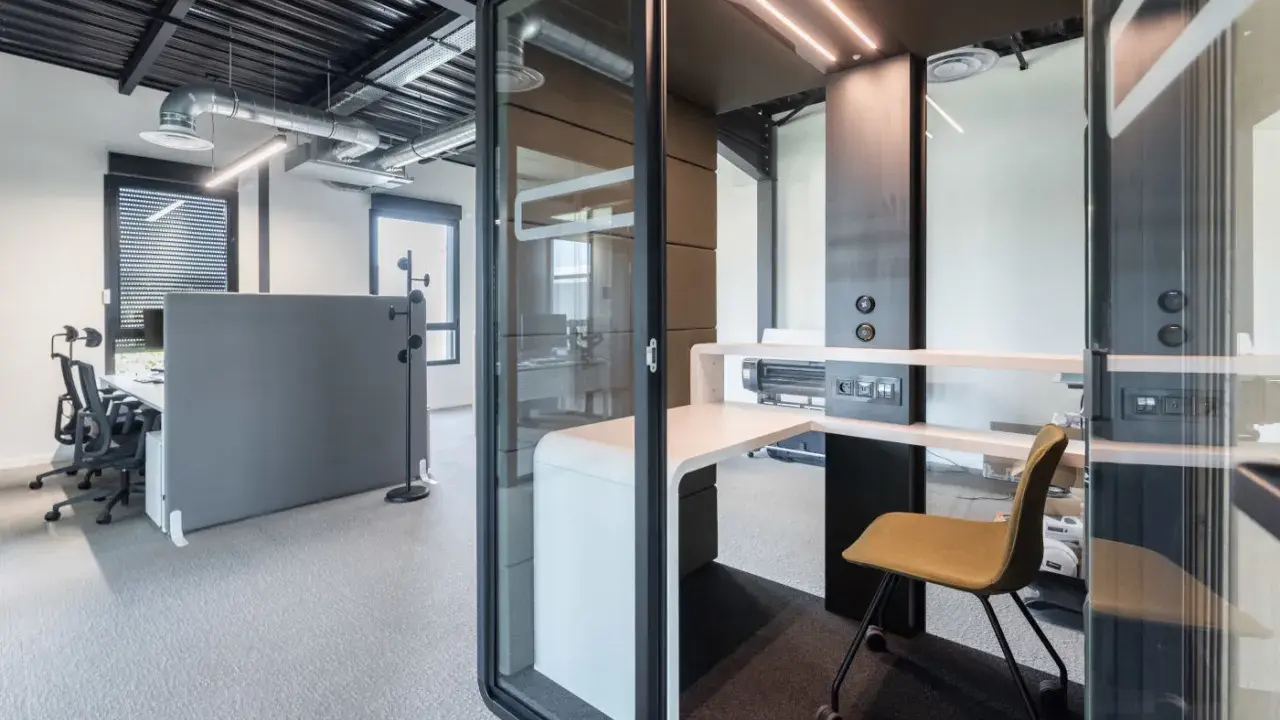 Un bureau moderne avec des cabines acoustiques et du mobilier flex office, idéal pour la concentration.