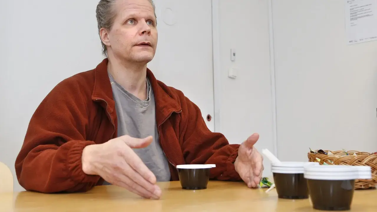Kaj Linna gestikulerar vid ett bord med tre små mörka koppar framför sig.