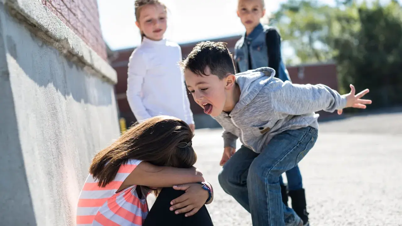 Niña acosada por otros niños en la calle.