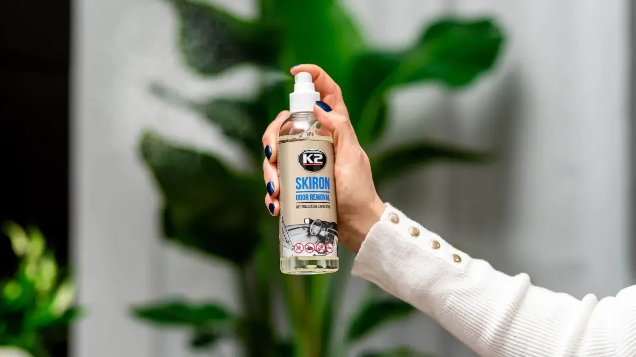 Dłoń trzyma butelkę K2 SKIRON ODOR REMOVAL, która rozpyla mgiełkę, by zlikwidować nieprzyjemny zapach w pokoju po nocy.