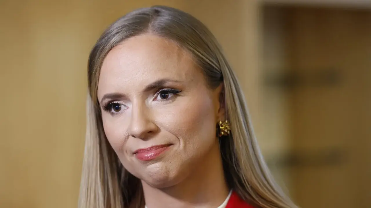 Sara Skyttedal, med sitt blonda hår och röda kavaj, ler snett mot kameran.