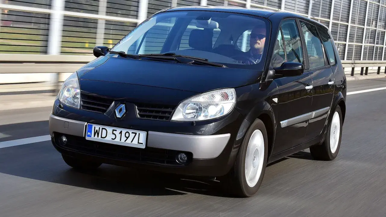 Czarny Renault Scenic 2 1.6 16v jedzie autostradą. Kierowca w okularach przeciwsłonecznych prowadzi auto.