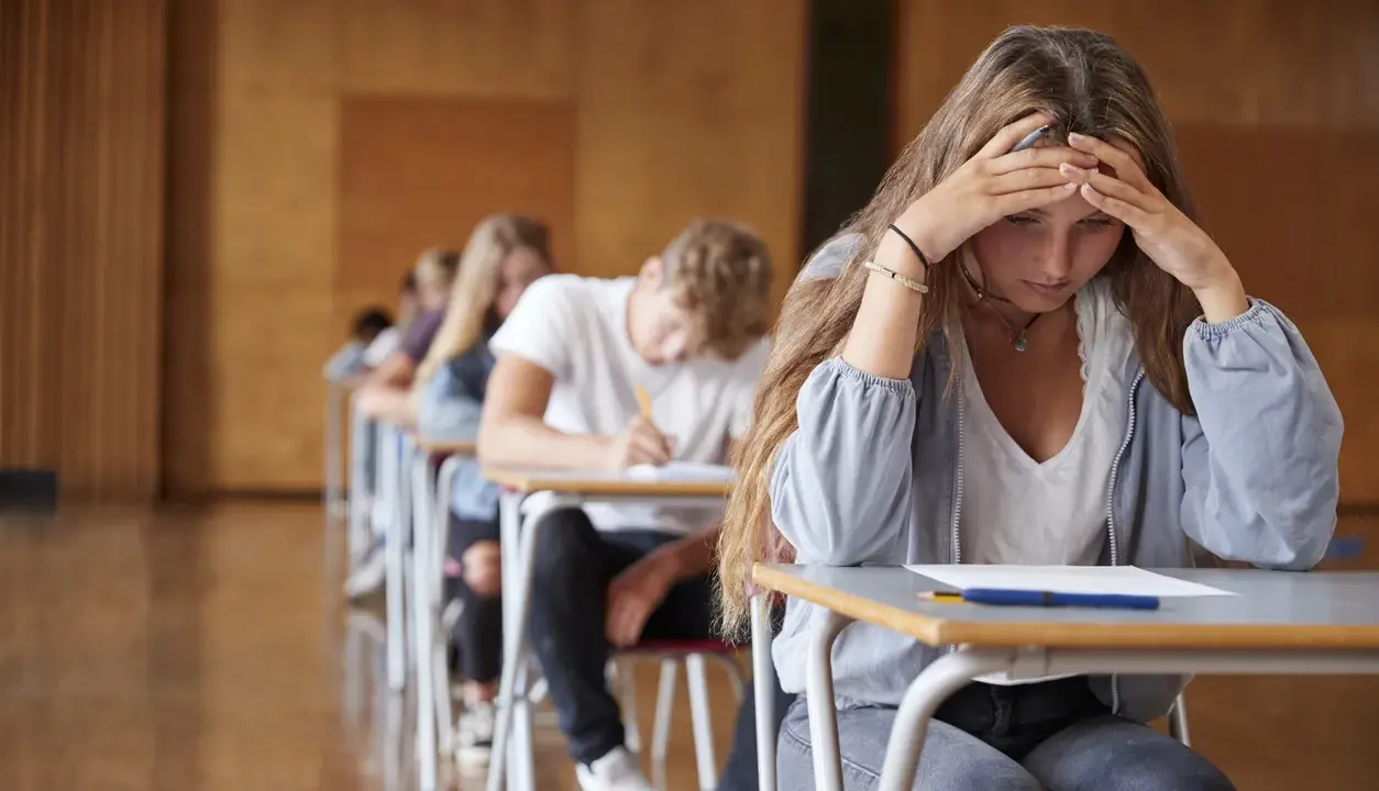 En tjej med händerna mot pannan känner efter studenten ångest under ett prov.