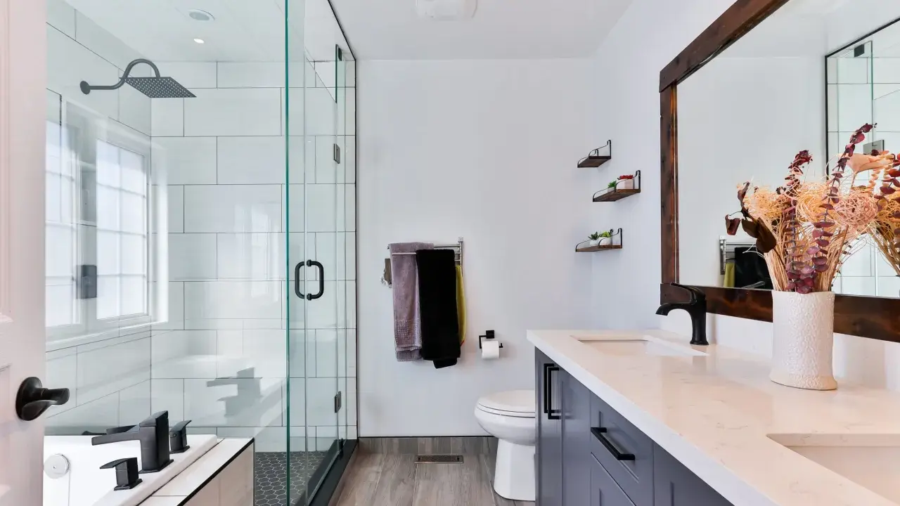Baño moderno con ducha de cristal, inodoro, lavabo doble y un gran espejo. Las ventanas para baños pequeños son clave para la luminosidad.