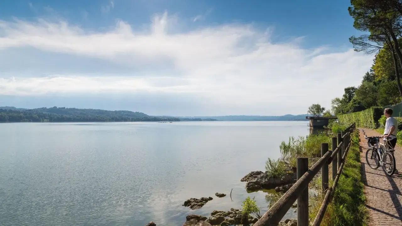 Ciclista ammira un lago in Lombardia, godendosi una delle tante ciclabili panoramiche.