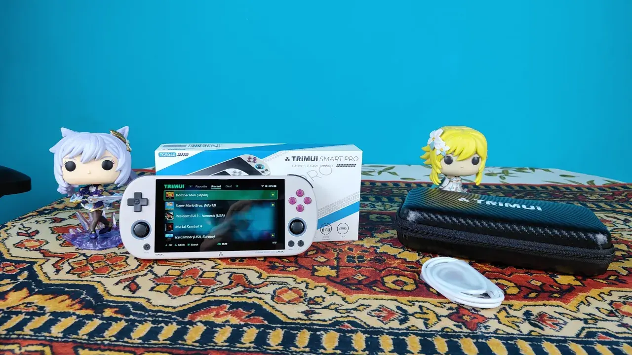 Biały handheld Trimui Smart Pro z grami, figurki Funko Pop i etui na konsolę.