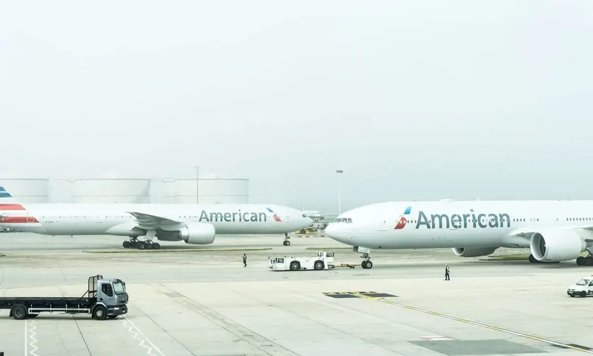 Dwa samoloty American Airlines na płycie lotniska, gotowe do przyjęcia bagażu rejestrowanego.