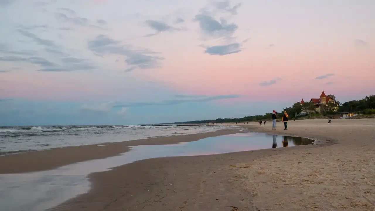 Zachód słońca nad morzem w Łebie. Piękne łeba atrakcje, plaża, zamek i spacerujący ludzie.