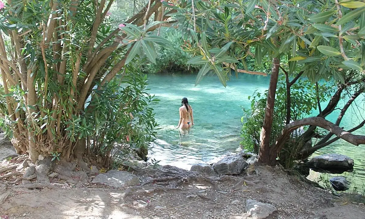 Una mujer se baña en la cueva del gato, un oasis de aguas cristalinas rodeado de vegetación exuberante.