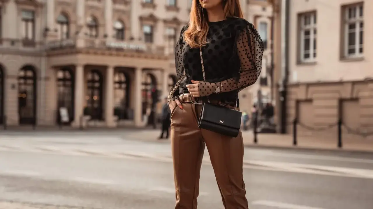 Elegancka stylizacja: czarna bluzka w kropki i brązowe skórzane spodnie. Idealne połączenie, by zadać pytanie: jaka bluzka do skórzanych spodni?