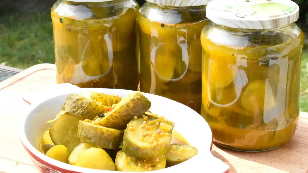 Słoiki z ogórkami z curry i miseczka z pokrojonymi ogórkami. Idealne na letnie przetwory.