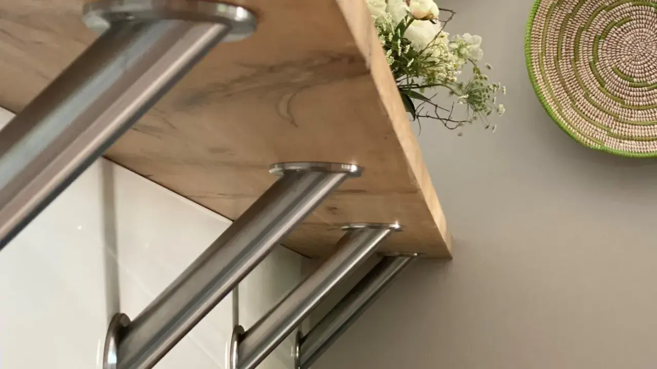Stabile Metallwinkel befestigen die Holztheke auf der Arbeitsplatte. Ein Blumenstrauß ziert die Oberfläche.