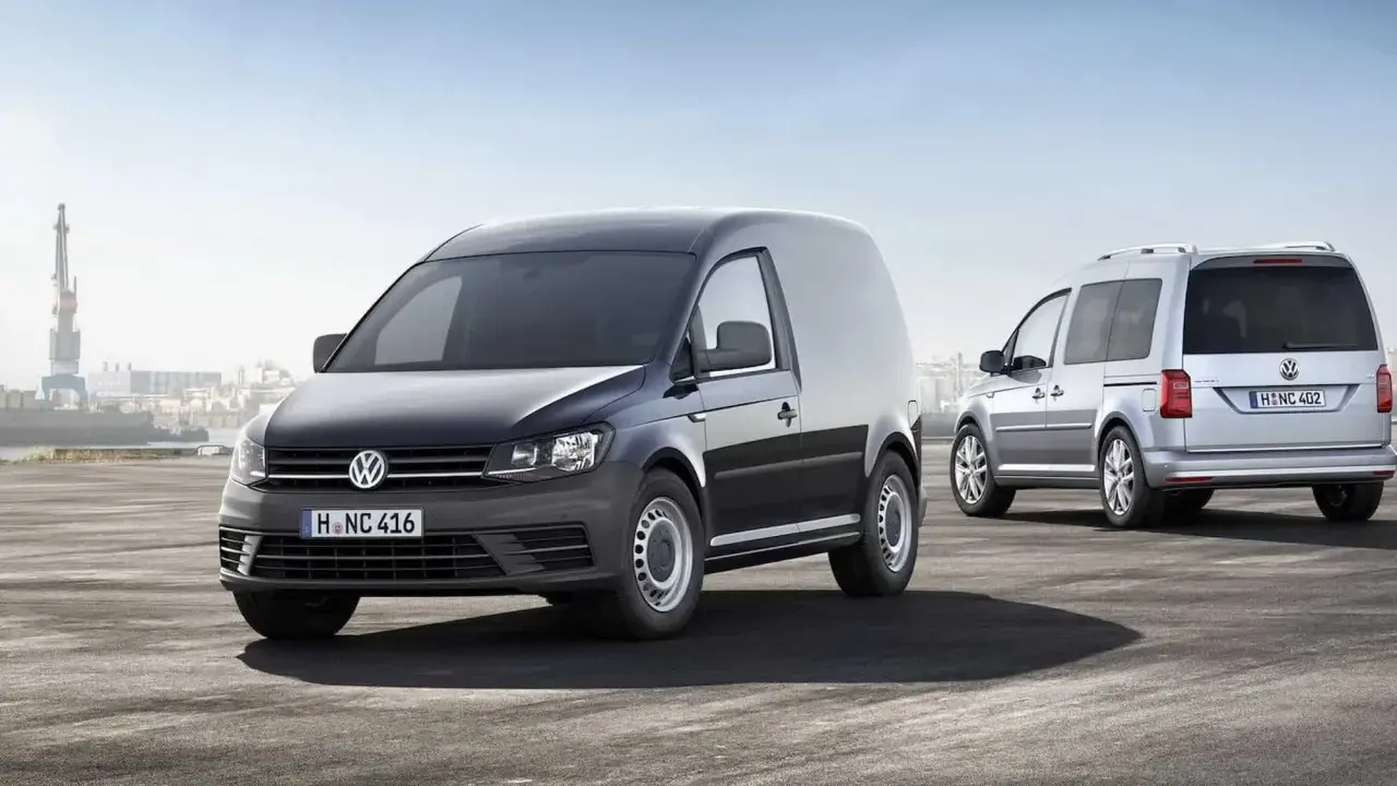 Dos furgonetas Volkswagen Caddy, una negra y otra plateada, demuestran su versatilidad como vehículo mixto adaptable en un entorno portuario.