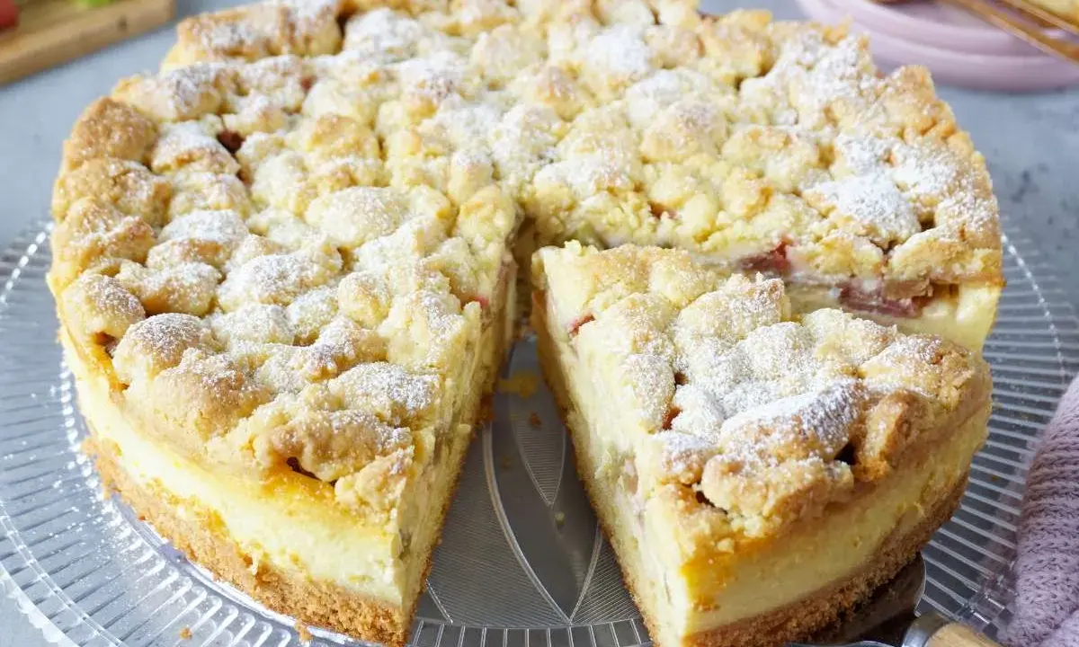 Saftiger Rhabarberkuchen mit Pudding und Streuseln, bestäubt mit Puderzucker. Ein köstlicher Genuss!