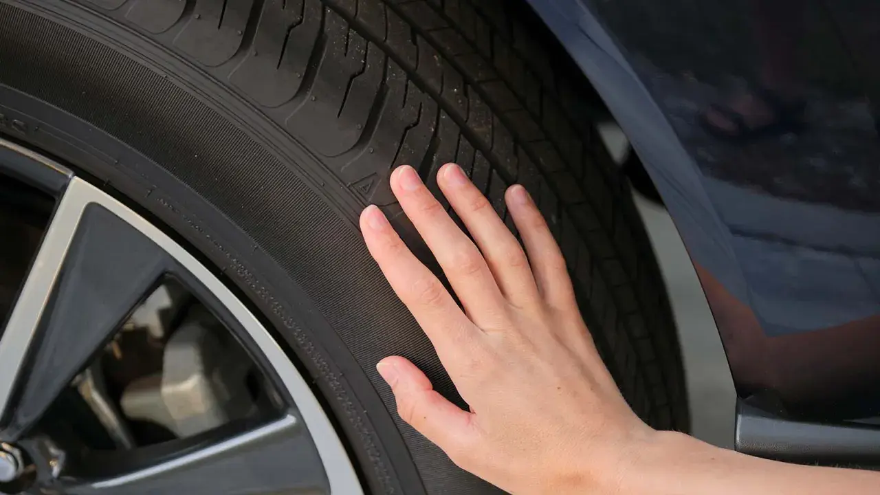 Una mano toca la banda de rodadura de un neumático, sugiriendo la pregunta de cuánto duran las ruedas de un coche.