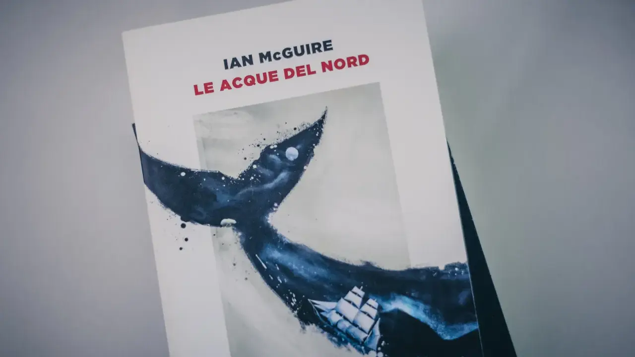 Copertina del libro "Le acque del nord" di Ian McGuire, con un veliero che naviga tra le onde scure e la coda di una balena.