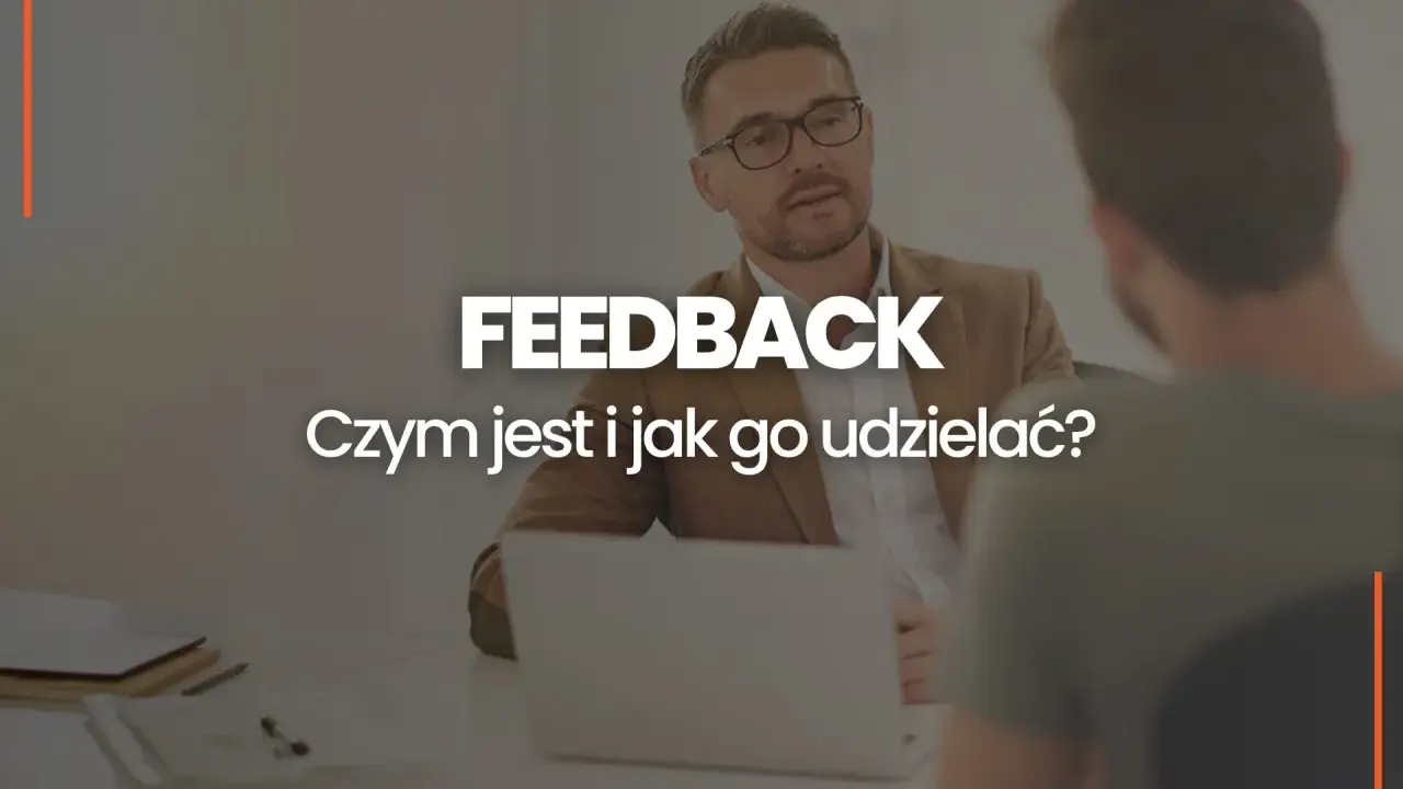 Dwóch mężczyzn przy biurku, jeden z nich udziela feedbacku. Czym jest feedback i jak go udzielać?