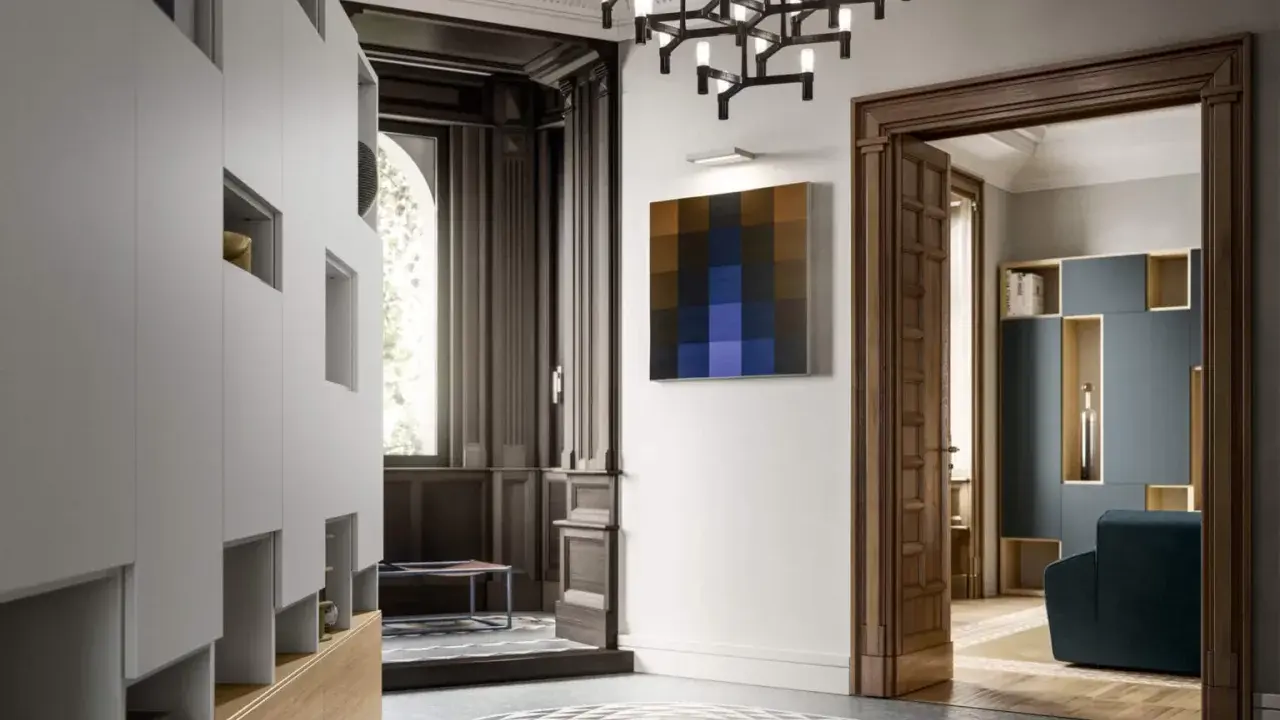 Ingresso con armadiature moderne, lampadario geometrico e un quadro astratto, in un ambiente che evoca lo stile liberty moderno.