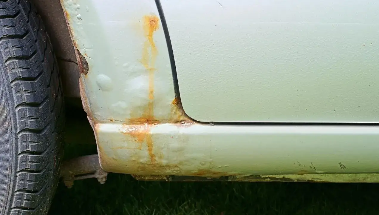 Rdza na progu samochodu i pęcherze pod lakierem. Aby zapobiec korozji, należy regularnie konserwować auto.