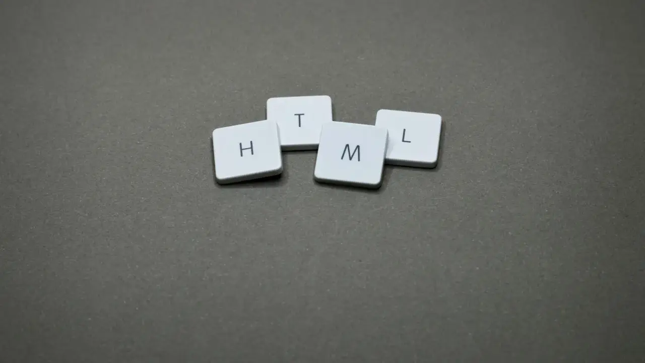 Białe kafelki z literami H, T, M, L ułożone na szarym tle, tworząc słowo HTML.
