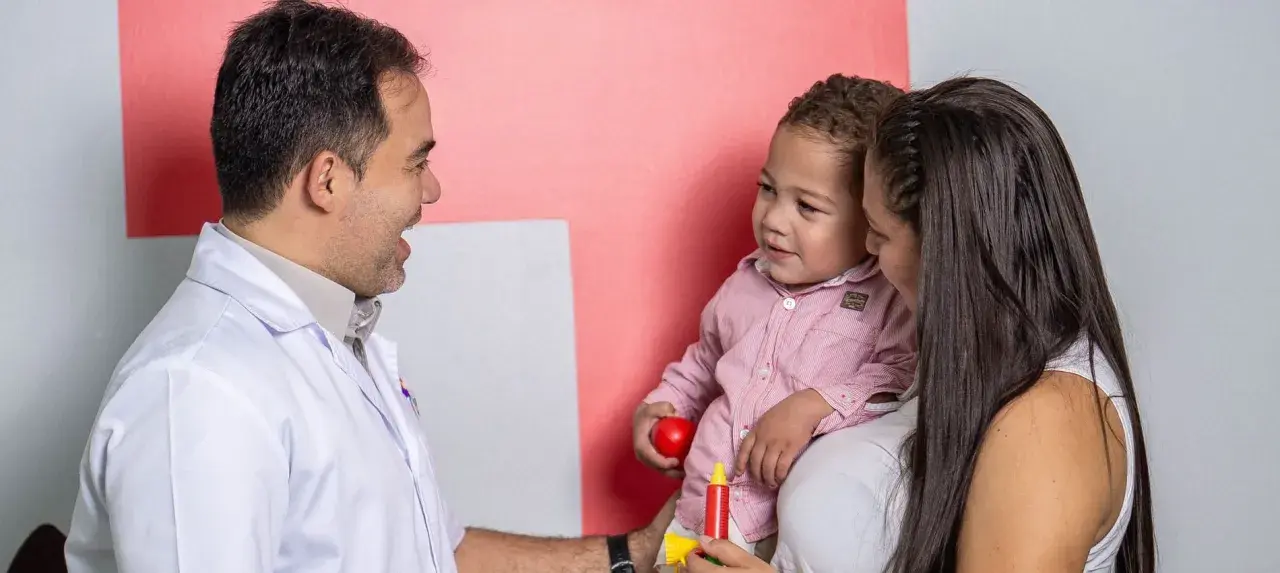 Médico habla con madre y niño, buscando entender los problemas de concentración del pequeño.