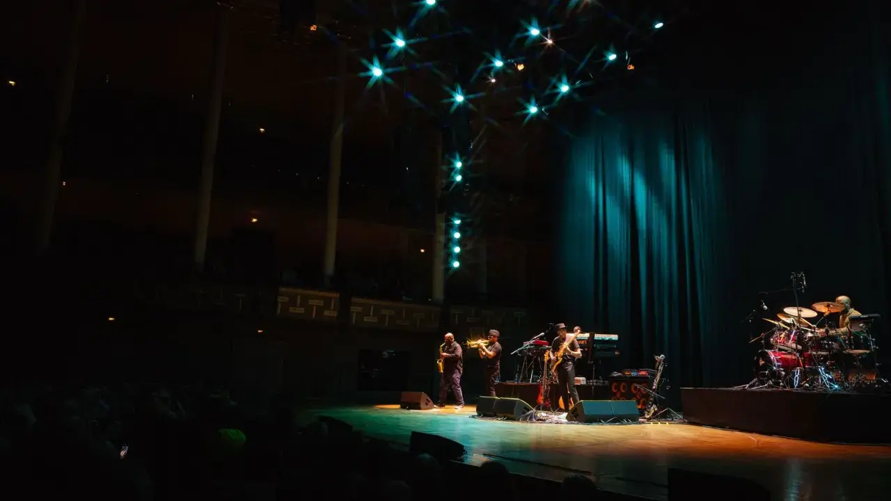 En jazzgrupp spelar på en scen under Stockholm Jazz Festival. Ljusen lyser upp scenen och publiken sitter i mörkret.