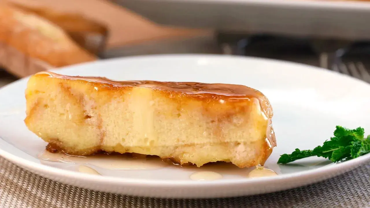 Un trozo de pan de calatrava bañado en caramelo, con una hoja de menta al lado.