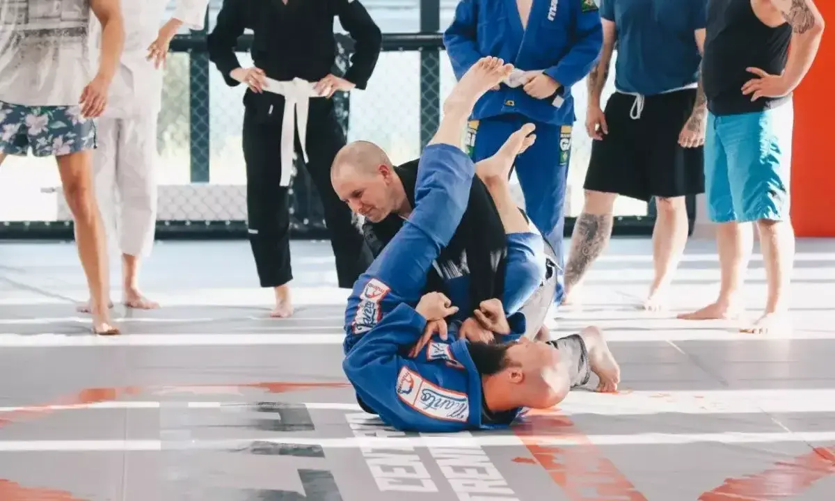 Dwóch mężczyzn w niebieskich kimonach ćwiczy chwyty na macie. To właśnie bjj co to za sztuka walki, która uczy kontroli i poddań.