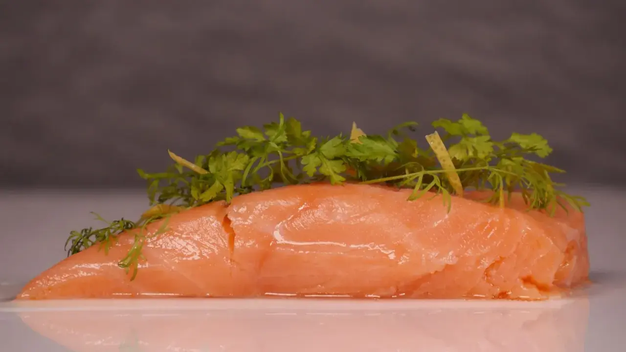 Zartes Lachsfilet, sous vide gegart, mit frischen Kräutern und Zitronenzesten garniert.