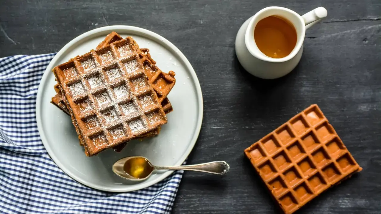 Gaufres de farine de châtaigne saupoudrées de sucre glace, servies avec du miel doré. Un délice gourmand.