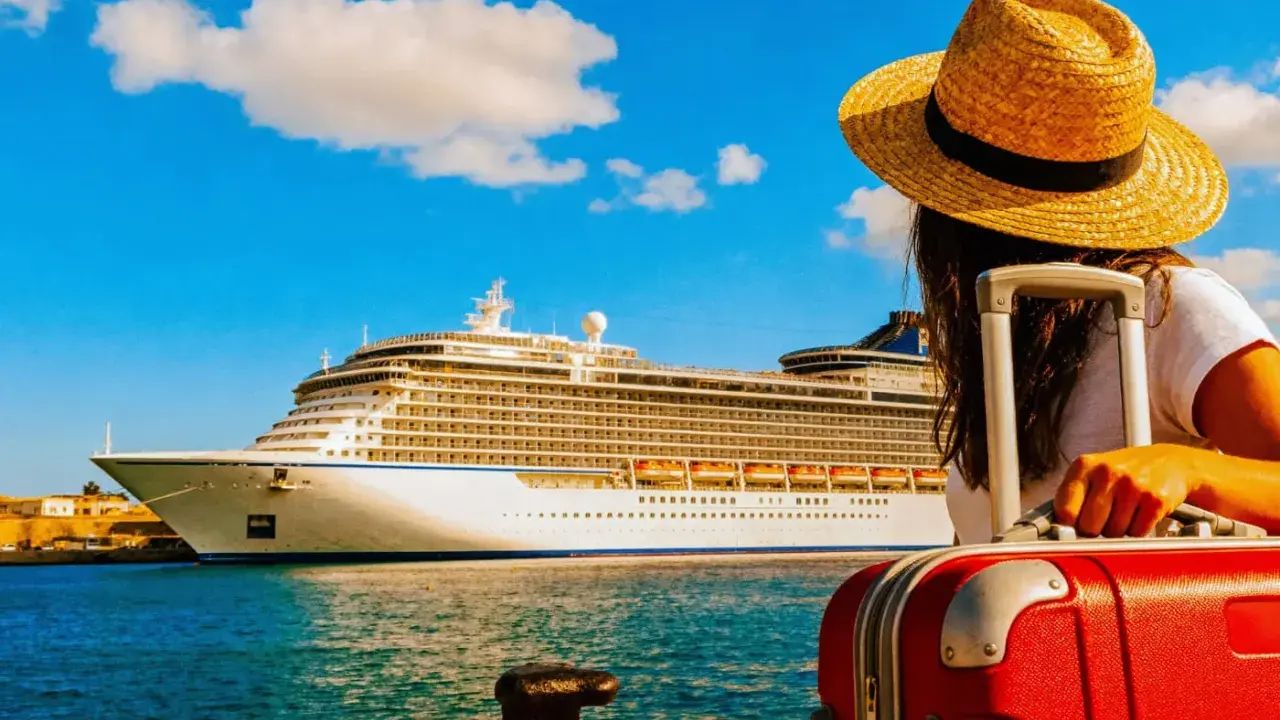 Donna con valigia rossa e cappello di paglia guarda una grande nave da crociera. Forse si paga per scendere dalla crociera.