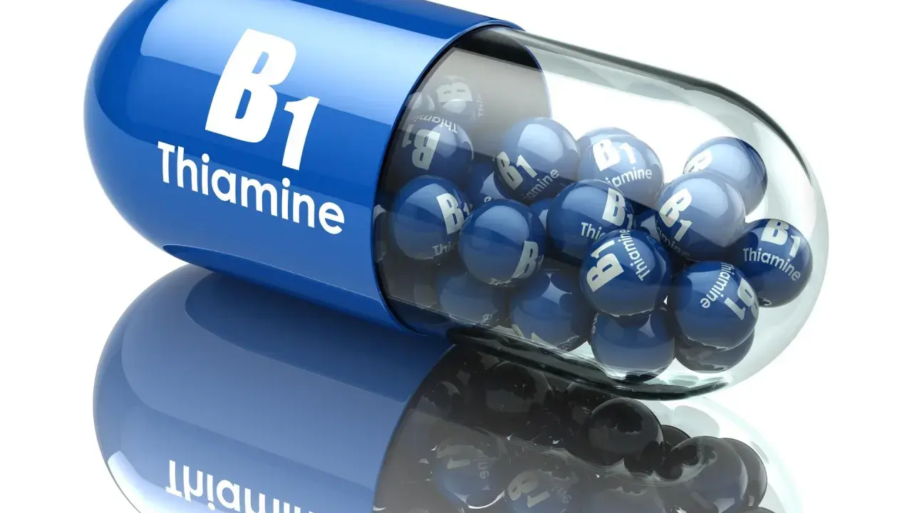 Duża, niebieska kapsułka z napisem "B1 Thiamine" wypełniona mniejszymi, niebieskimi kulkami z tym samym napisem. To jakby wizualizacja działania benfogamma forte.